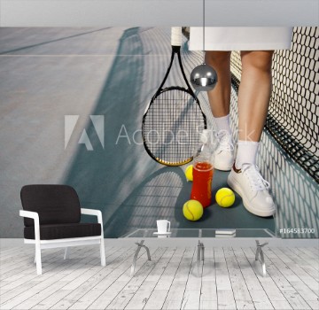 Picture of Tennis concept woman legs next to tennis balls and refreshing drink next to net copy space outdoors 
